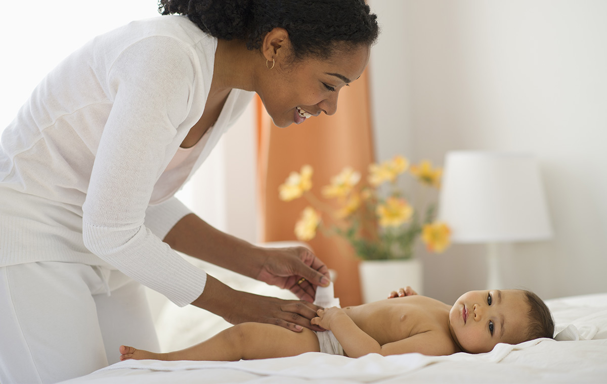 A woman that changes diaper on a baby.